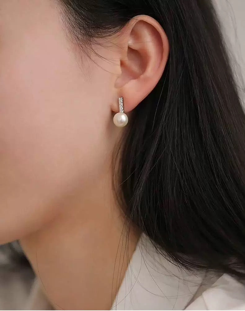 Pearl earring worn by a person with dark hair and light skin.