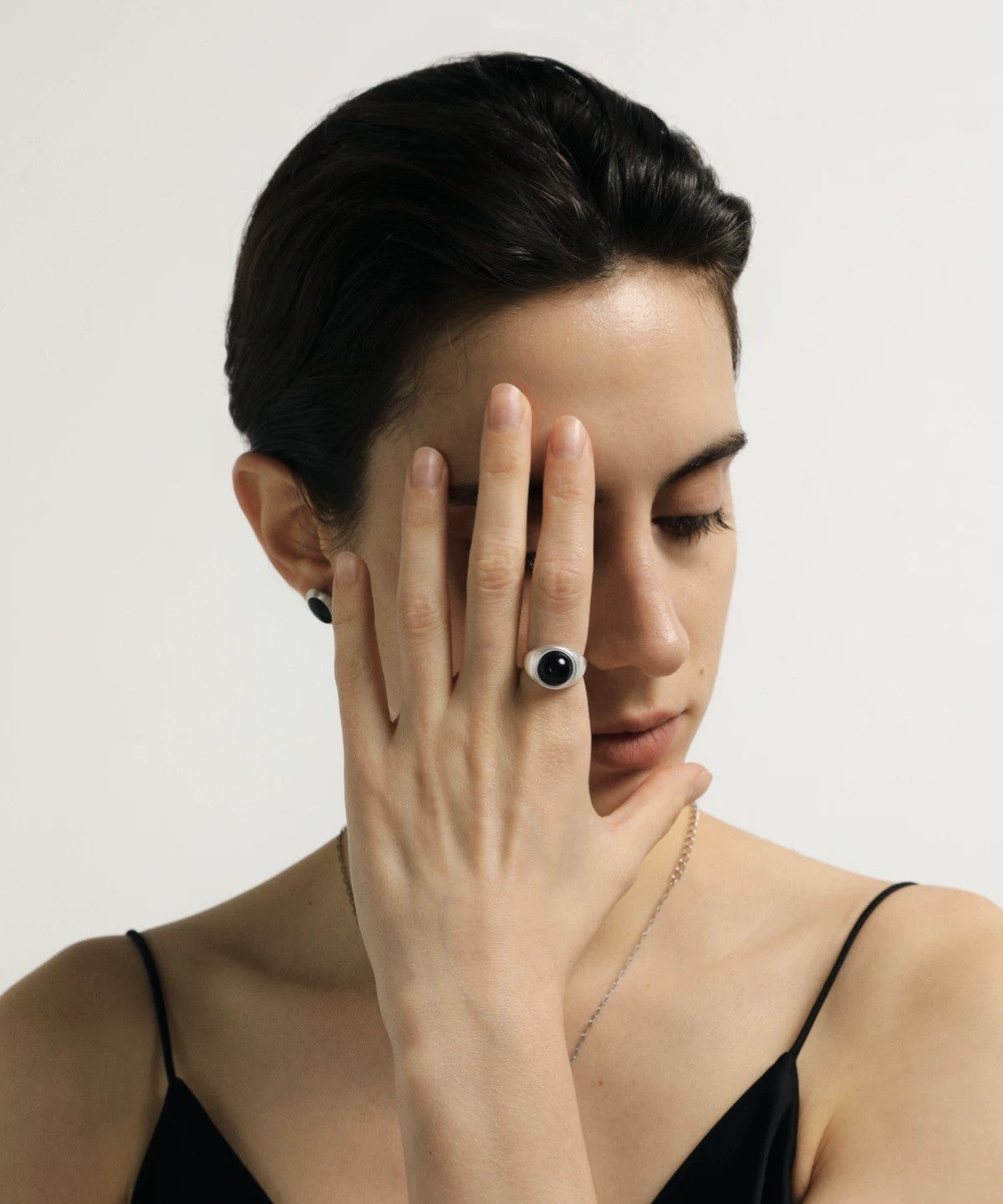 Woman wearing a black ring on her finger with a plain background