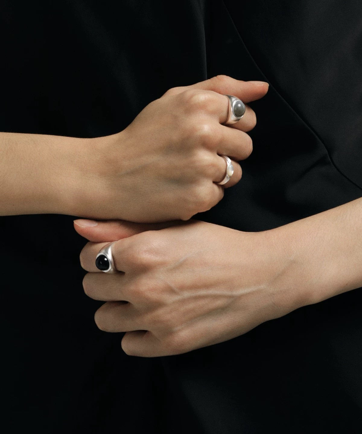 Two hands with rings on a black background