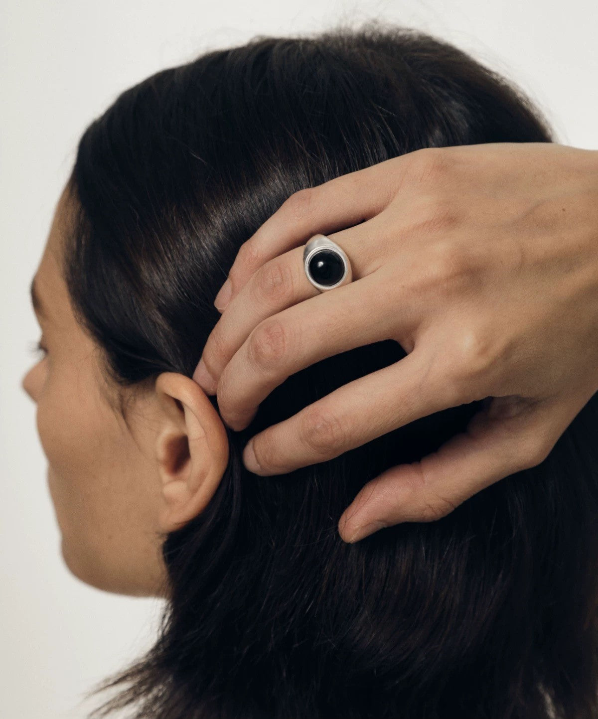 Person adjusting a hair clip on another person's hair against a neutral background