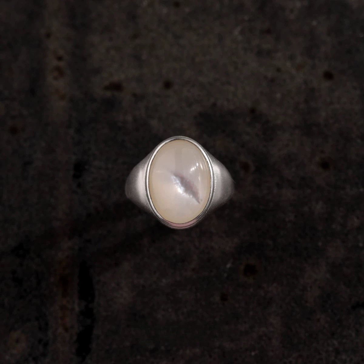 Silver ring with a round stone on a dark textured background