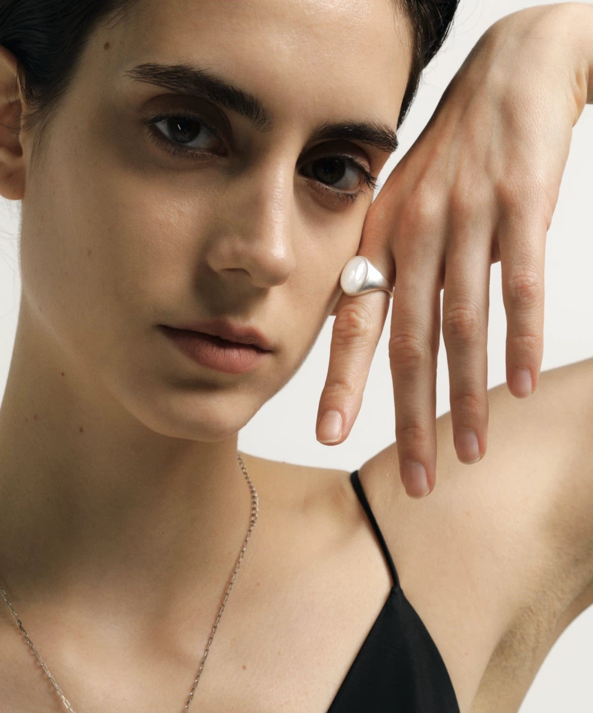Close-up of a person wearing a black top with a plain background