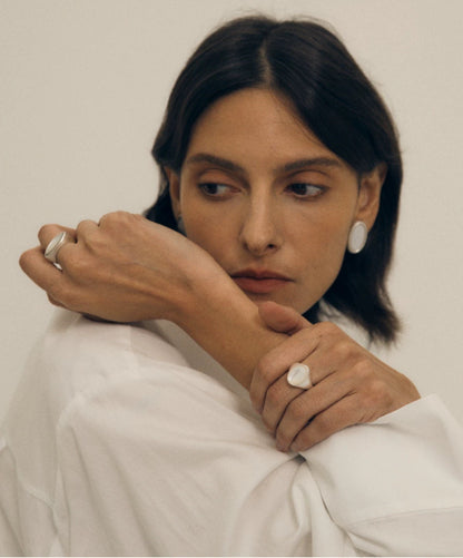 Woman wearing rings and earrings with a neutral background