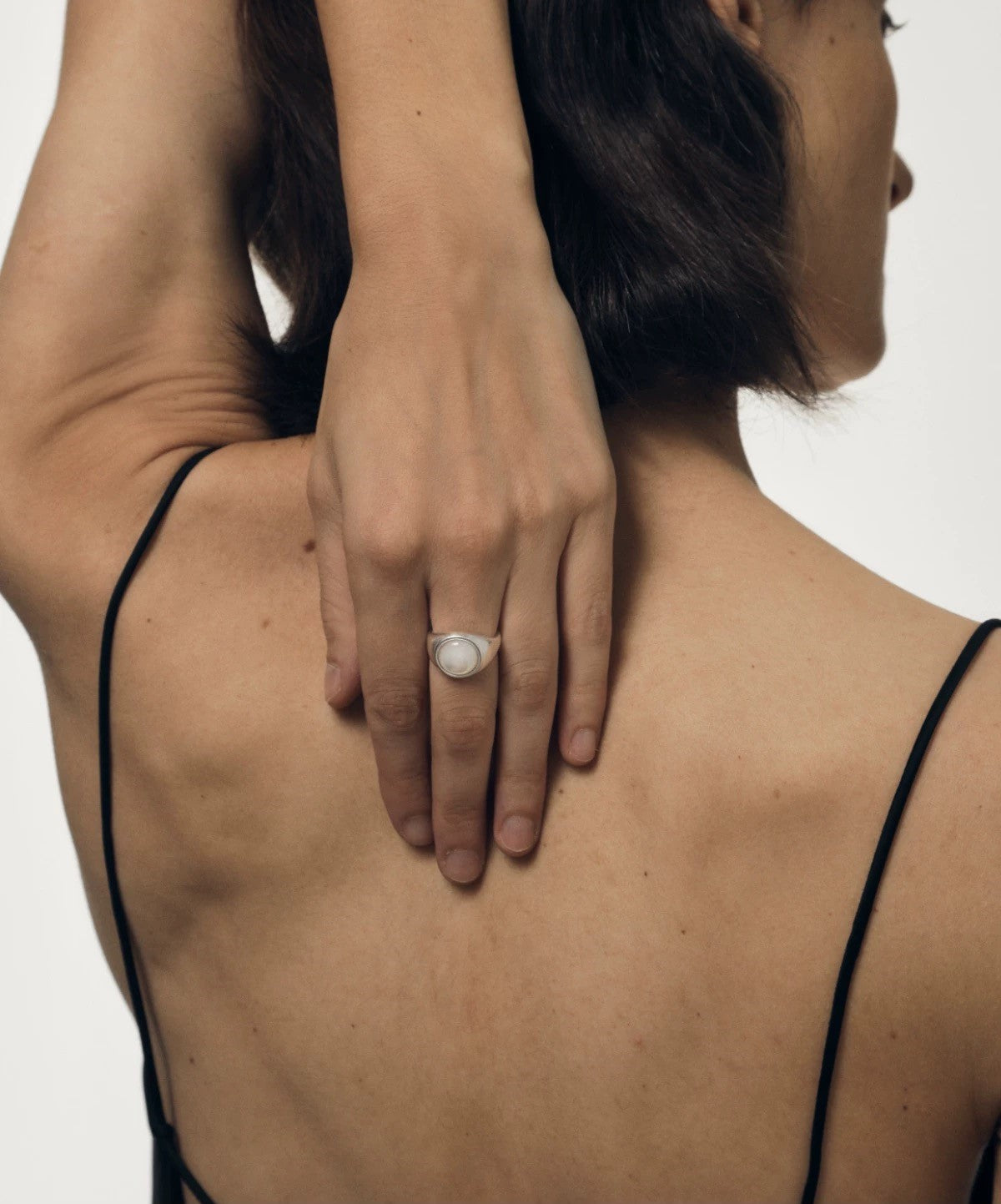 Person wearing a ring on their hand placed on another person's shoulder against a neutral background