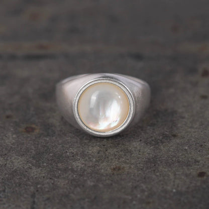 Silver ring with a central nacre on a textured gray background
