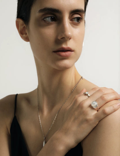 Woman wearing a necklace and ring on a plain background