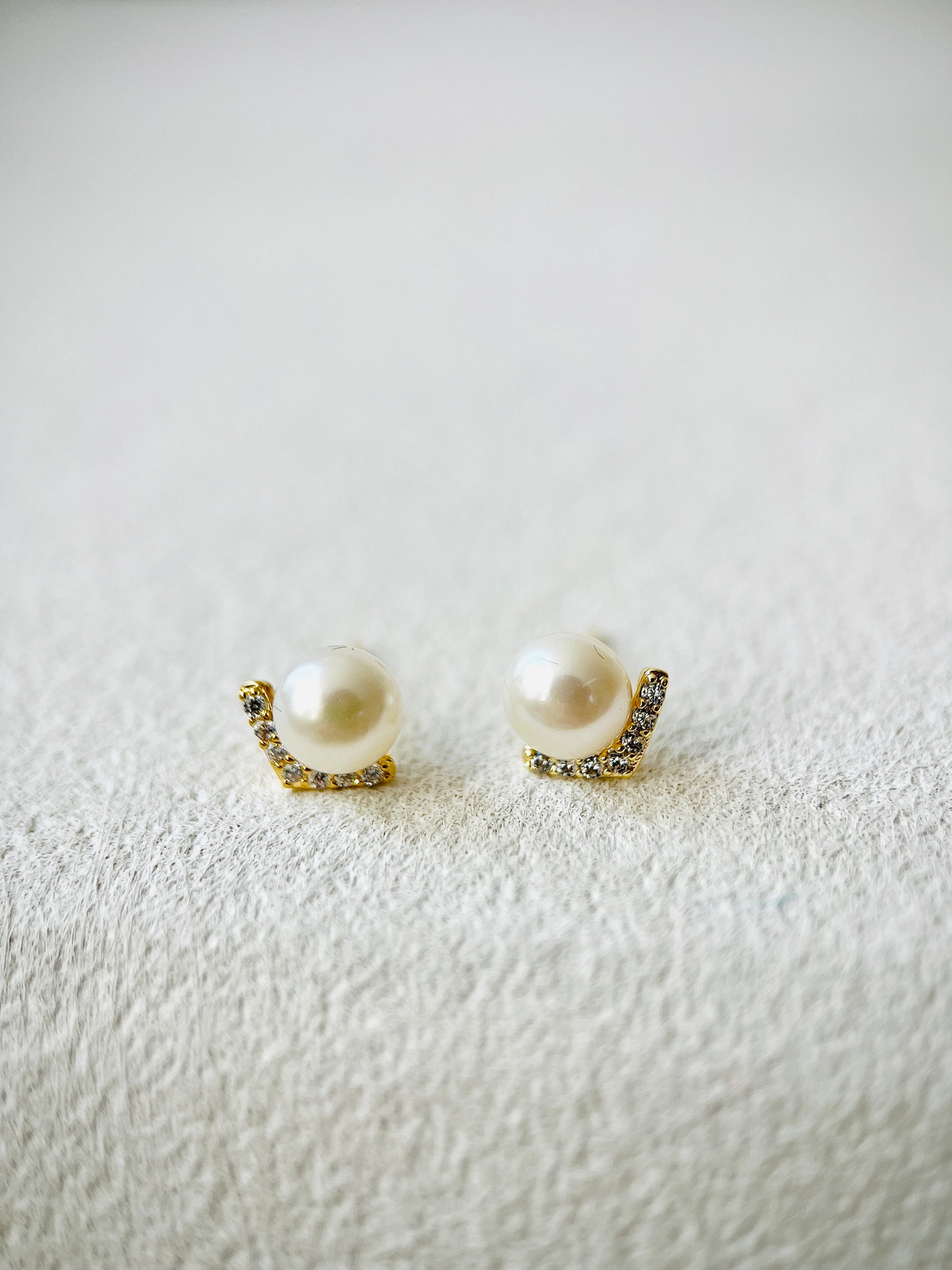 Pair of pearl earrings with gold accents on a textured white surface