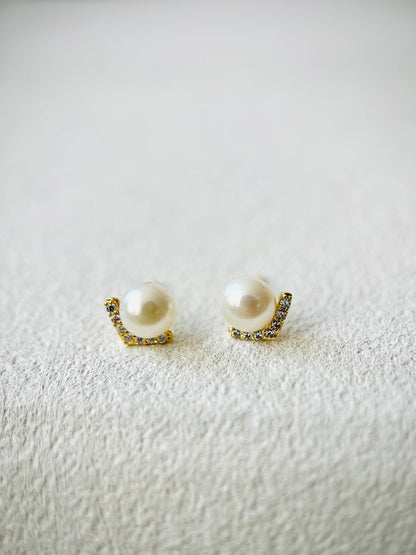 Pair of pearl earrings with gold accents on a textured white surface