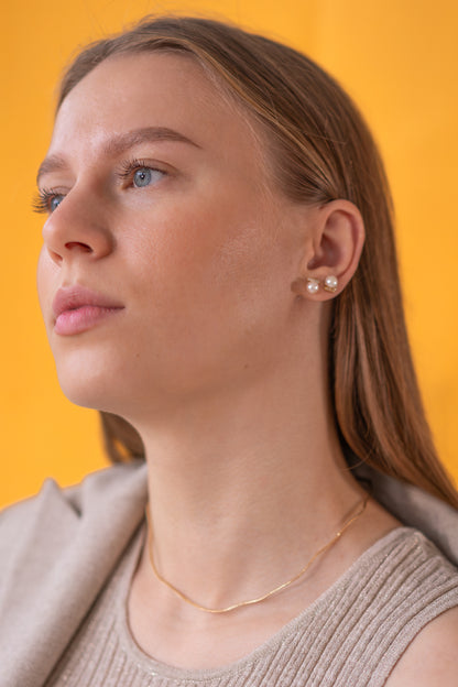 Woman wearing pearl earrings against a yellow background