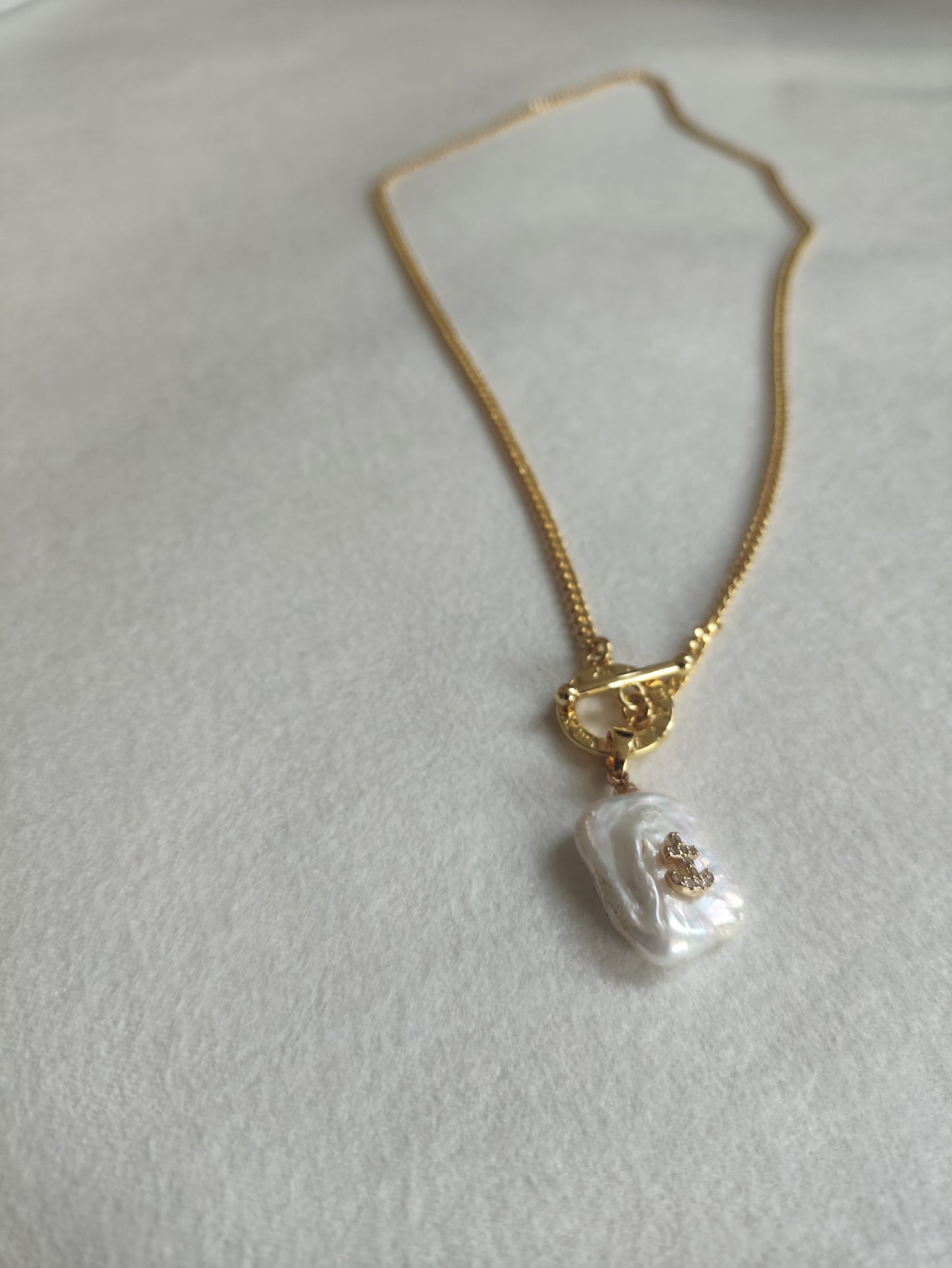 Pearl necklace for men with a gold chain on a light gray background