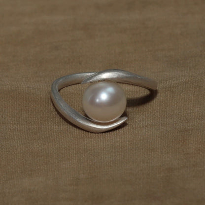Silver ring with a pearl on a brown fabric background