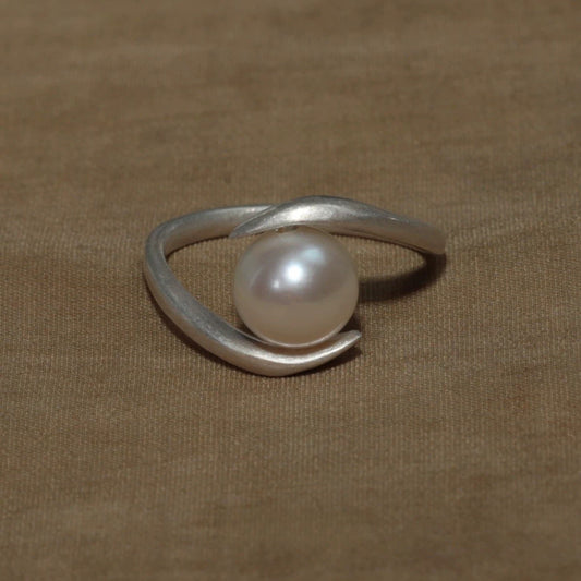 Silver ring with a pearl on a brown fabric background
