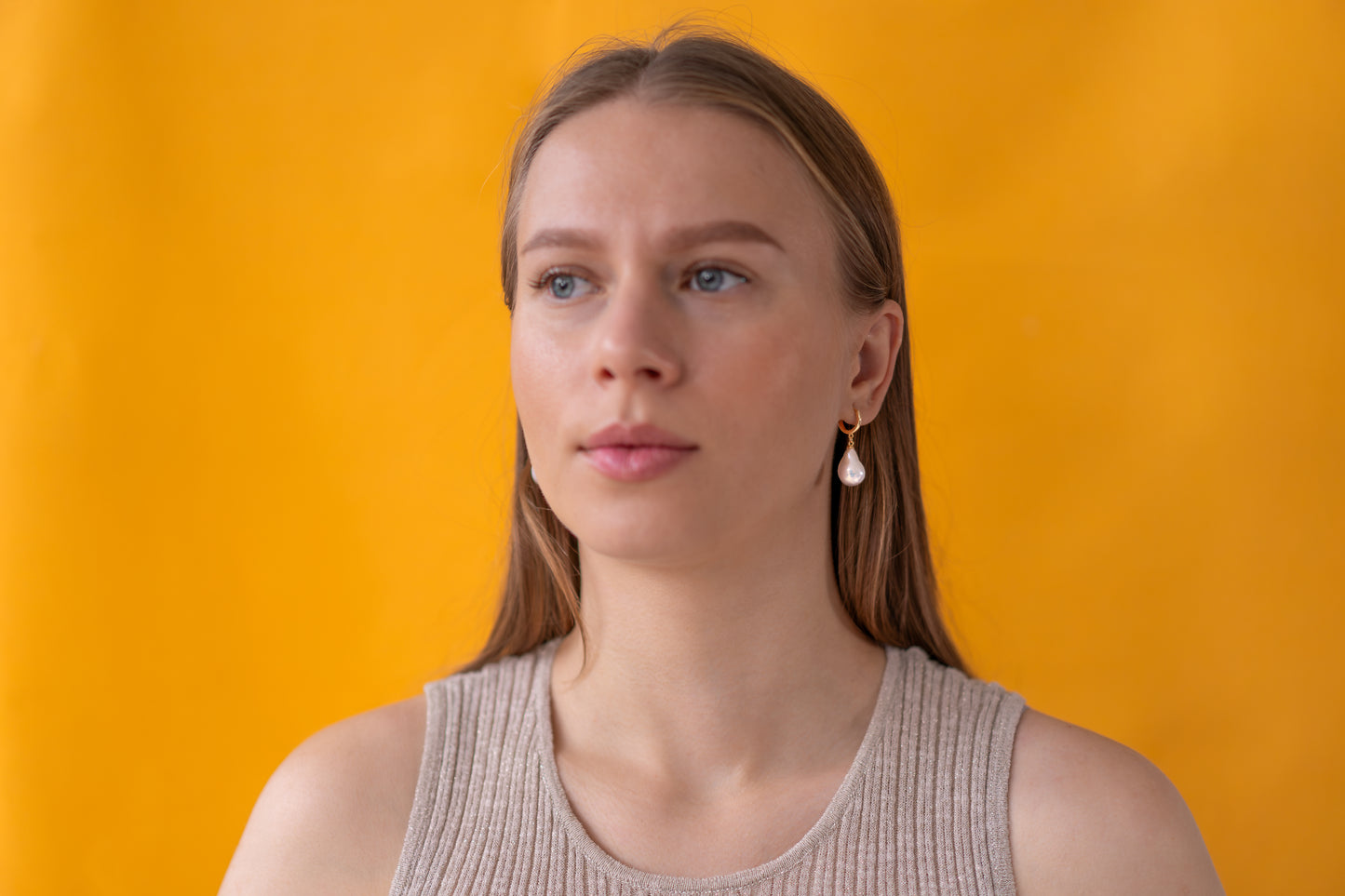 Woman wearing white baroque pearl earrings with gold hooks