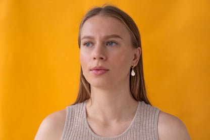 Woman wearing white baroque pearl earrings with gold hooks