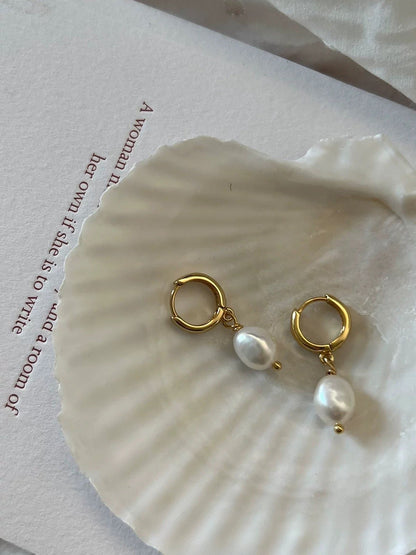 Gold hoop earrings with pearls on a shell