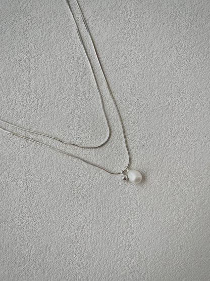 Necklace with a single pearl pendant on a light gray background