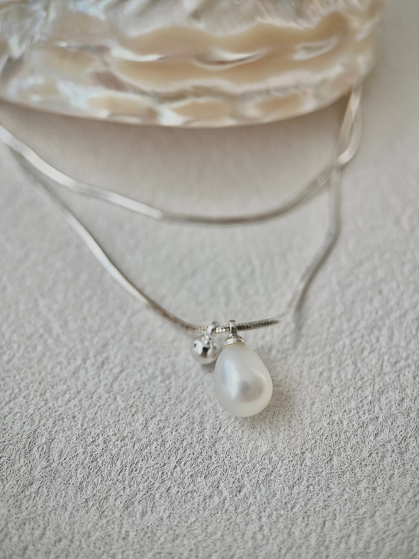 Pearl necklace with a silver chain on a textured surface