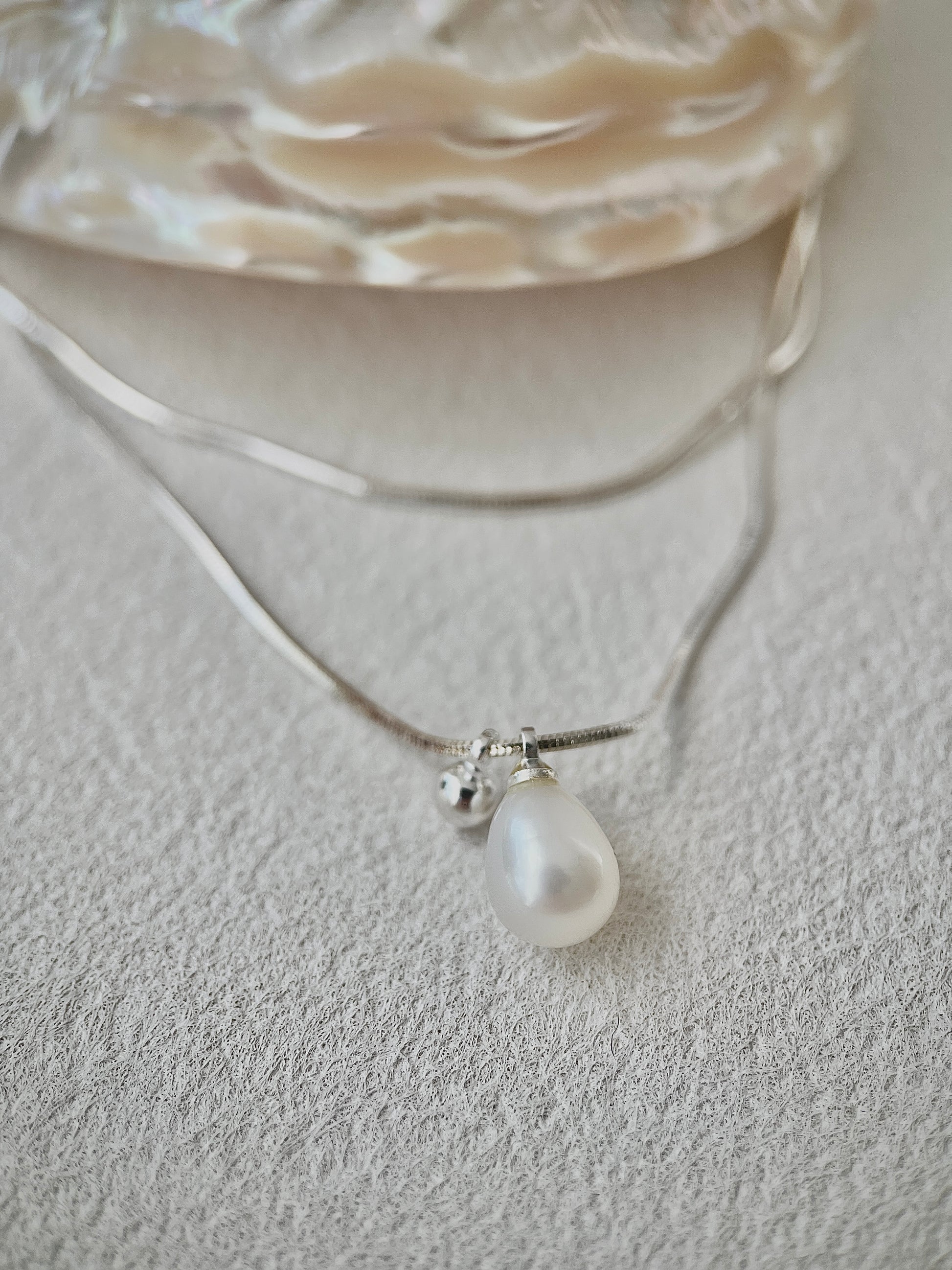 Pearl necklace with a silver chain on a textured surface