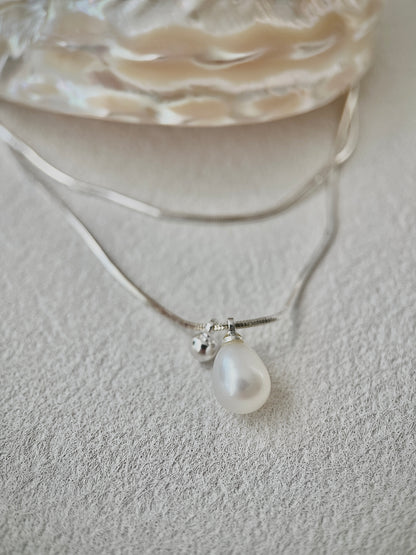 Pearl necklace with a silver chain on a textured surface