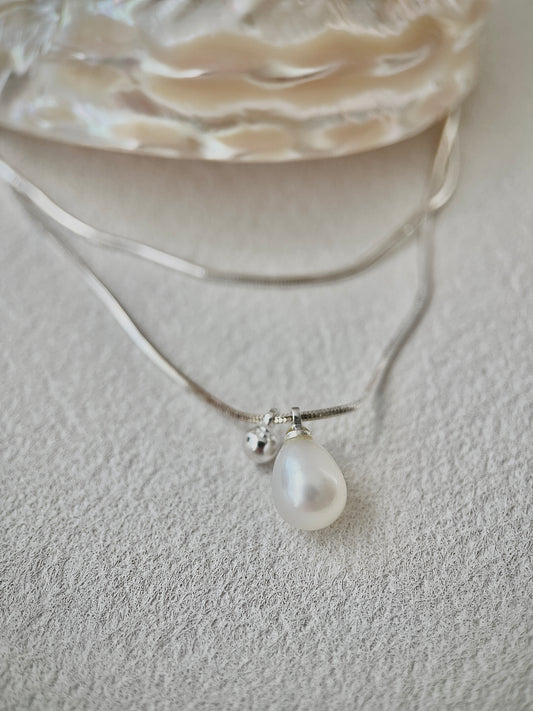 Pearl necklace with a silver chain on a textured surface