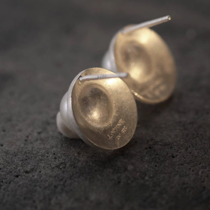 Pair of silver pearl earrings on a dark textured surface