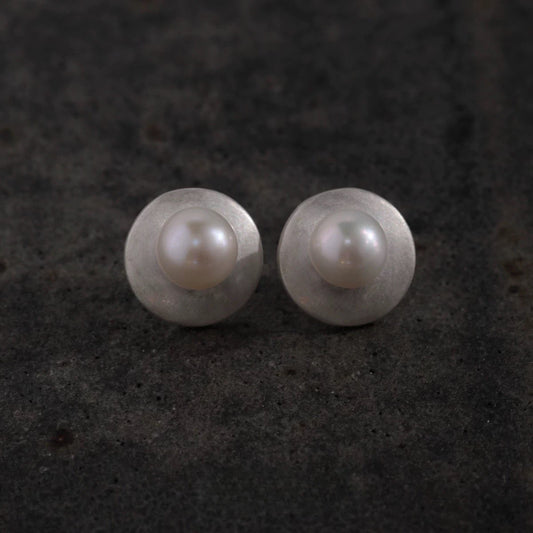 Pair of pearl earrings on a dark textured background