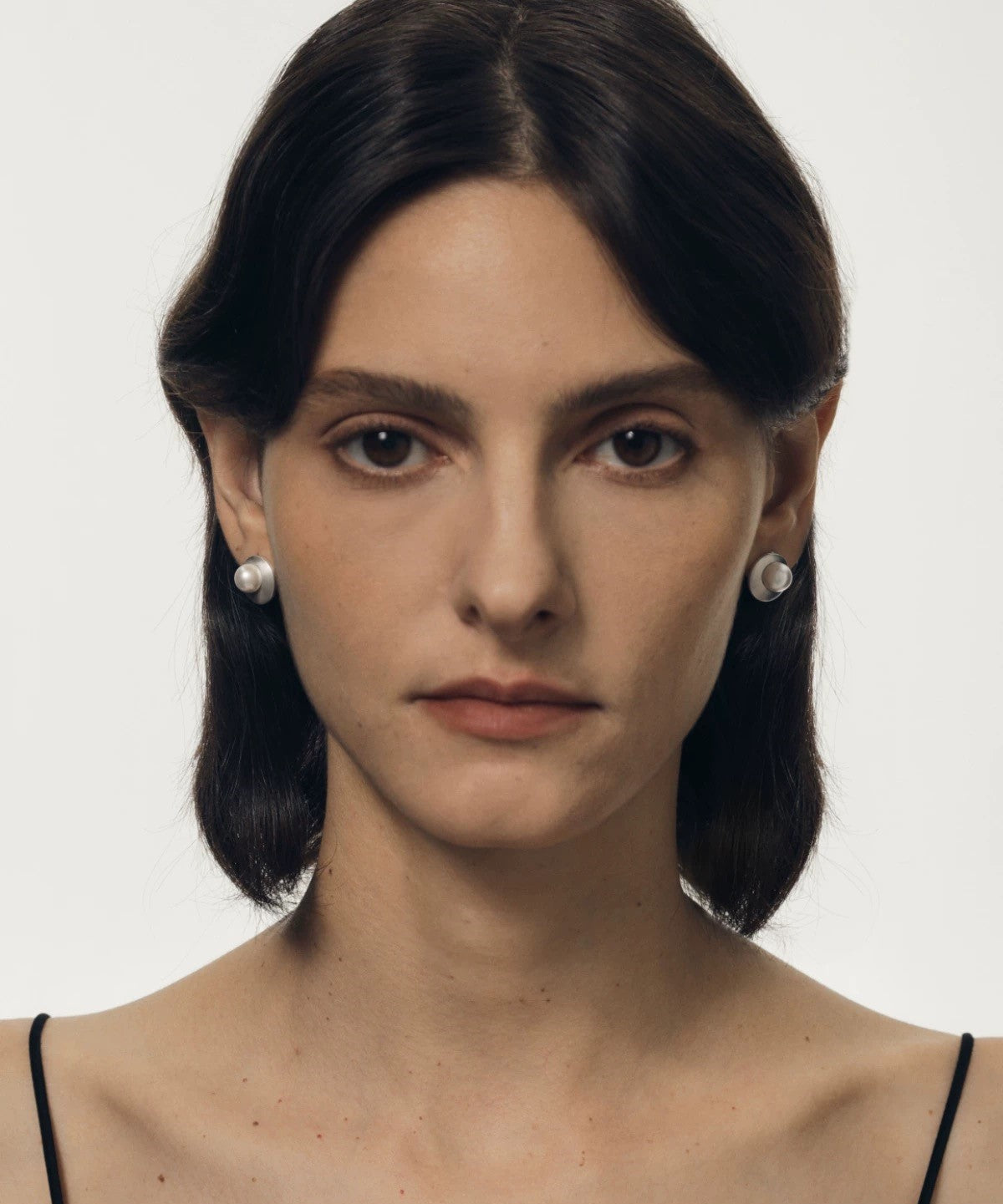 Woman wearing pearl earrings against a plain background