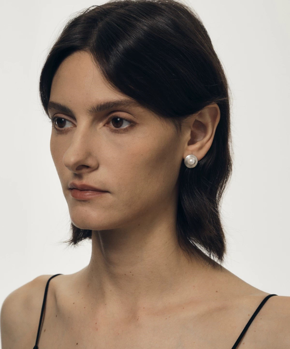 Woman wearing pearl earrings against a plain background