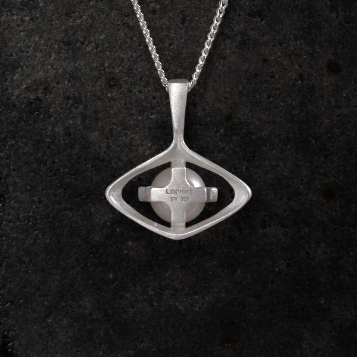 Silver pearl pendant necklace on a dark textured background