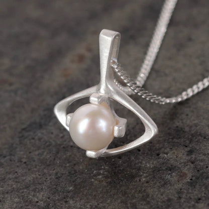 Silver pendant with a pearl on a dark textured surface