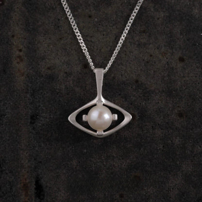 Silver necklace with a pendant featuring a pearl on a dark textured background
