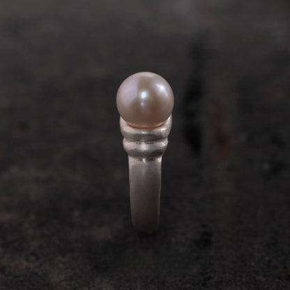 Silver ring with a pearl on a dark textured background