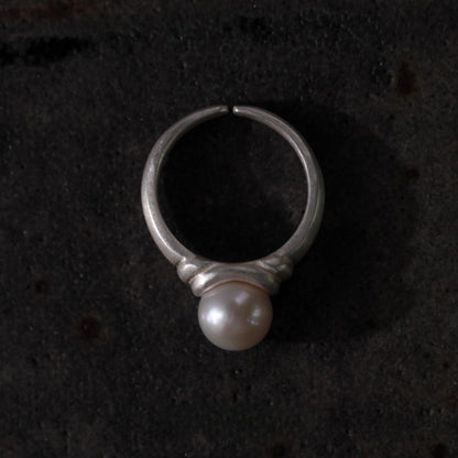 Silver ring with a pearl on a dark textured background