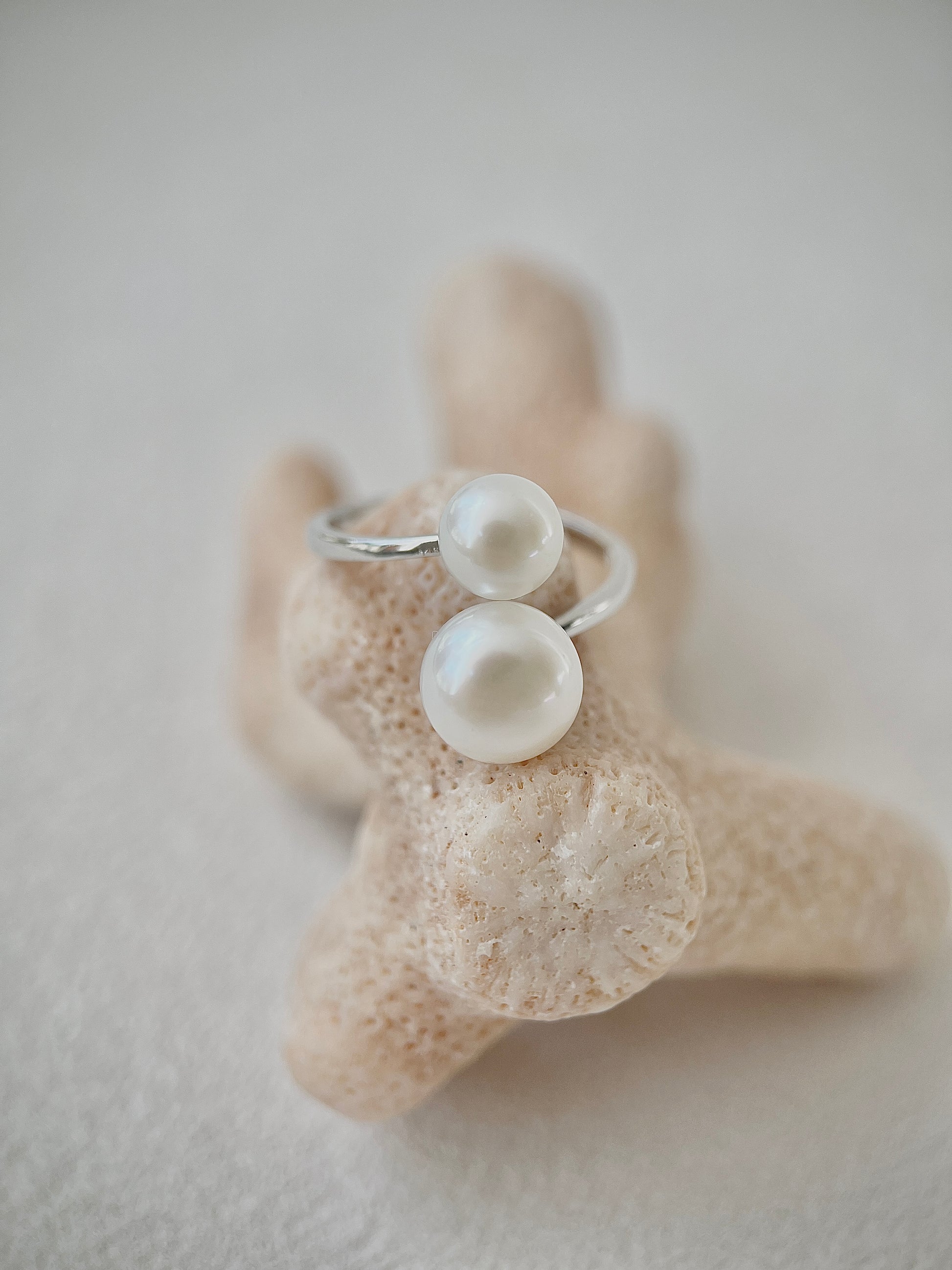Silver ring with pearls on a textured beige surface