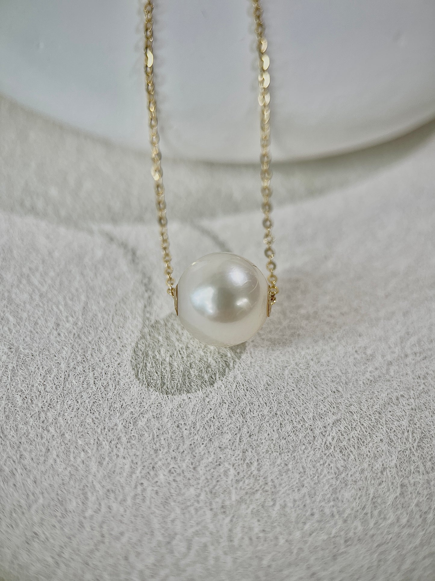 Pearl pendant necklace on a textured white surface