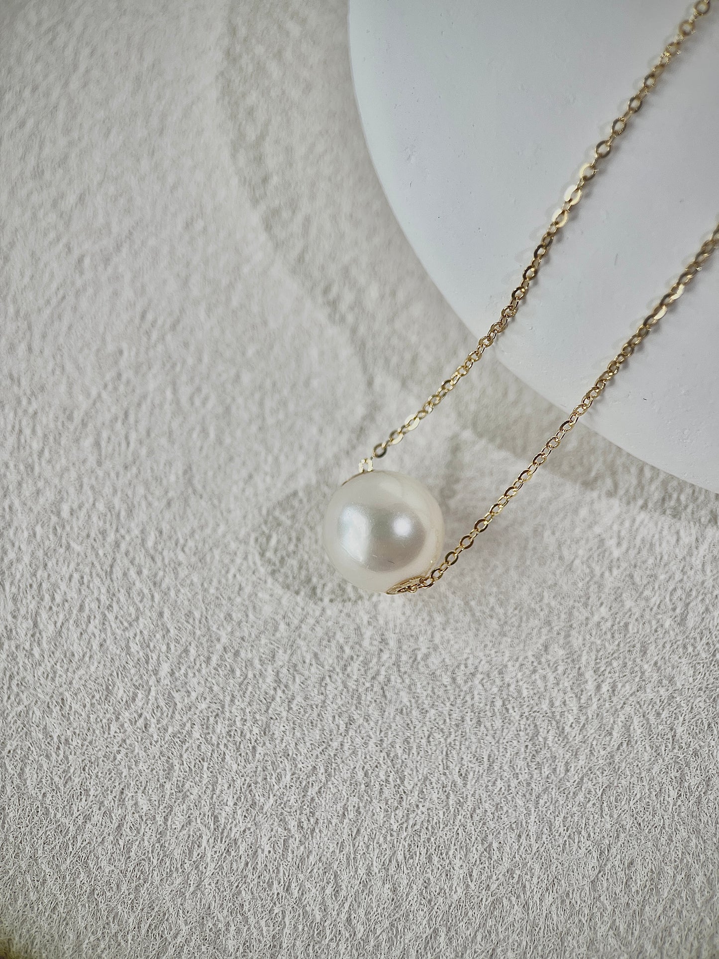 Pearl pendant necklace on a textured white surface