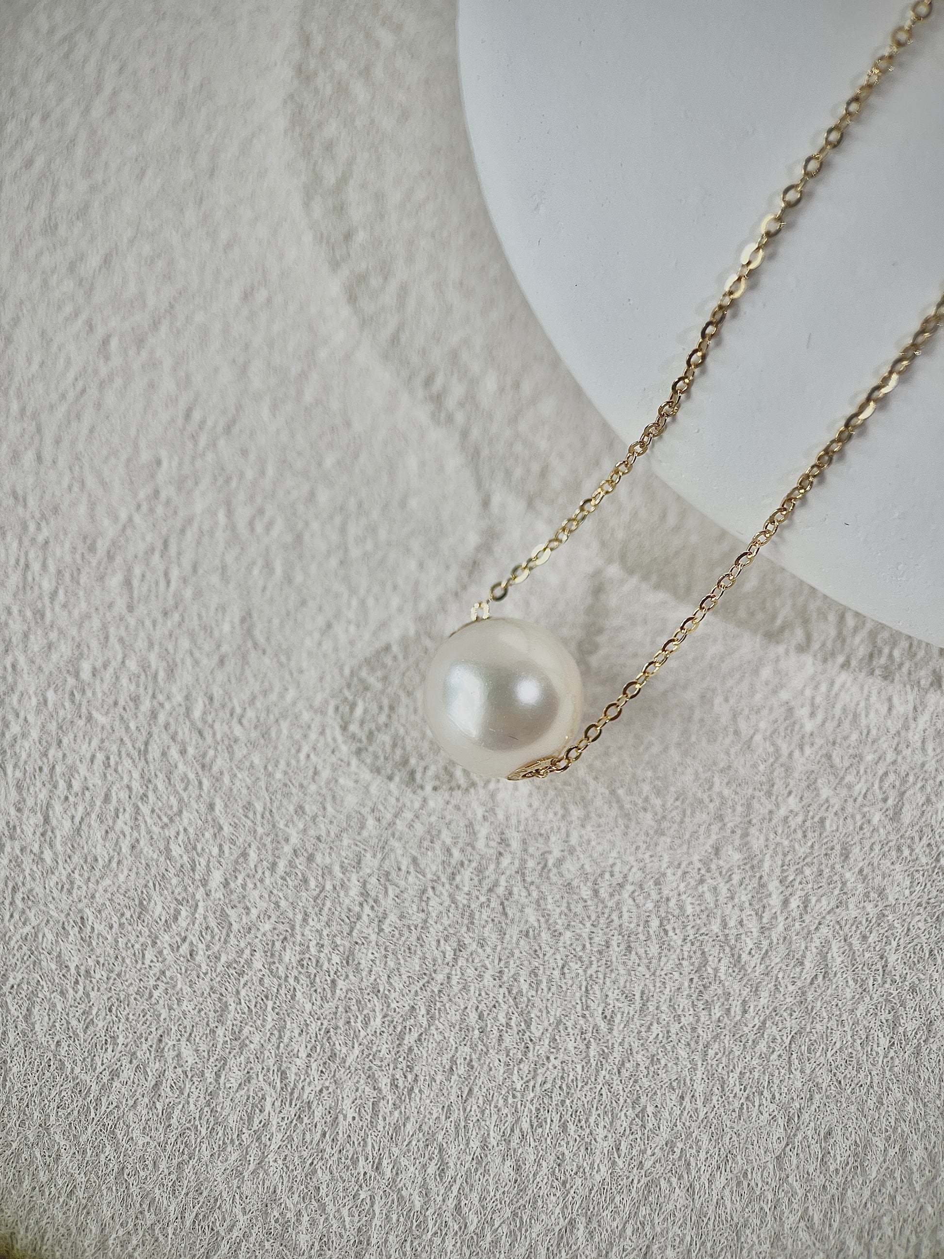 Pearl pendant necklace on a textured white surface
