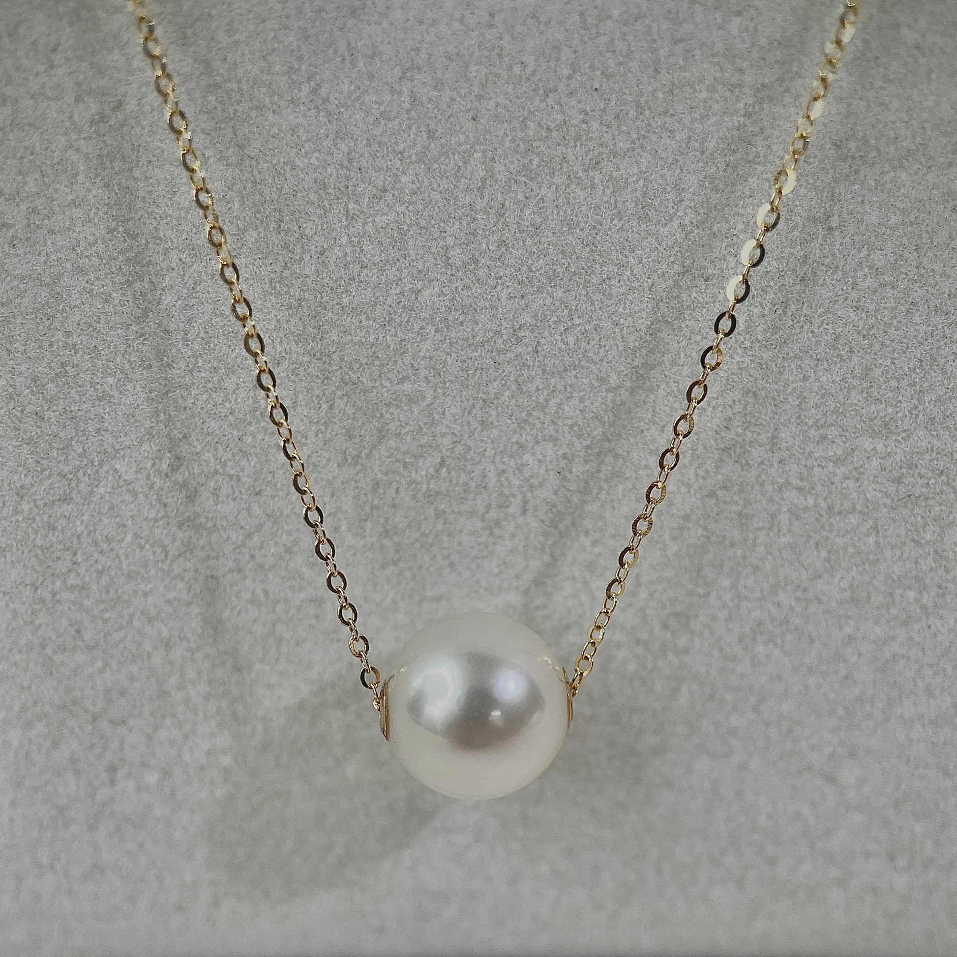 Pearl pendant necklace on a soft gray background