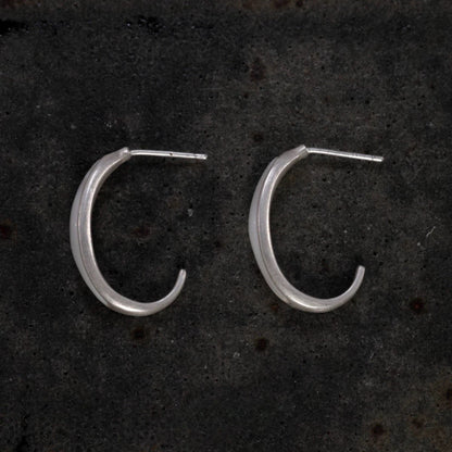 Silver hoop earrings on a dark textured surface