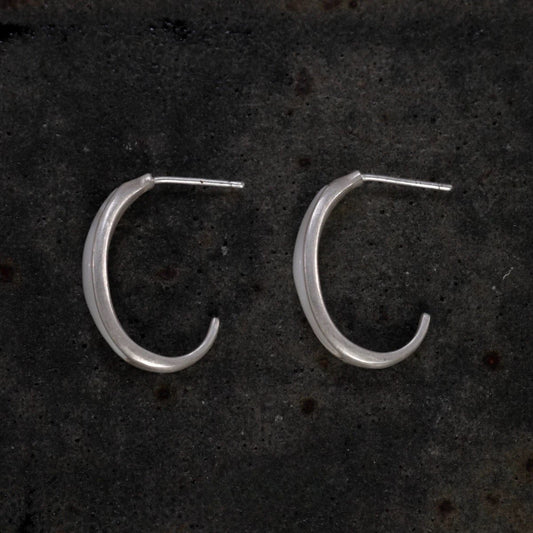 Silver hoop earrings on a dark textured surface