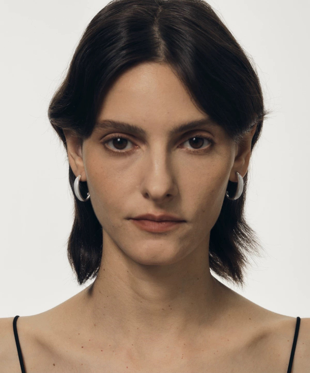 Woman wearing hoop earrings against a plain background