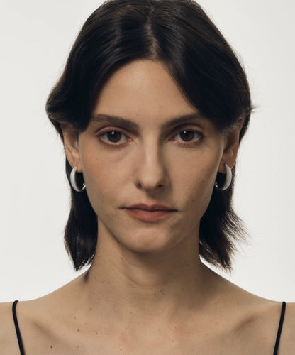 Woman wearing hoop earrings against a plain background