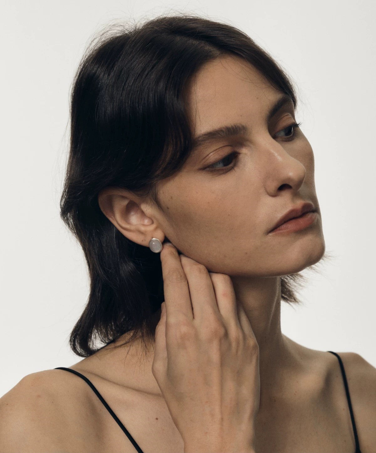 Woman wearing a pearl earring on a plain background