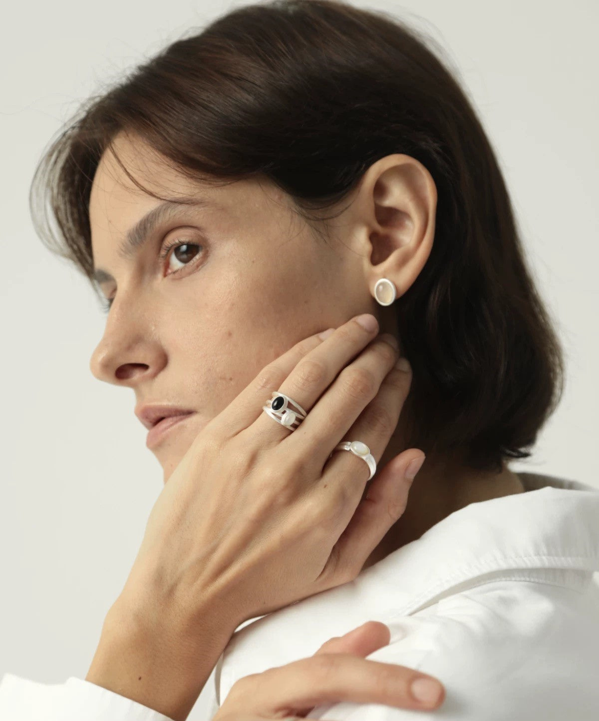 Woman wearing earrings and rings with a plain background