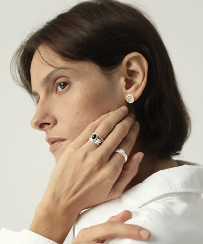Woman wearing earrings and rings with a plain background