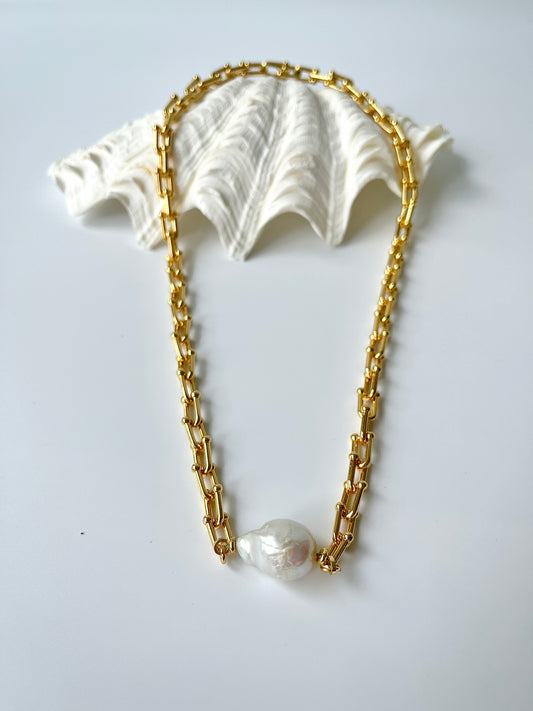 Gold chain necklace with white freshwater pearl pendants on a light gray background