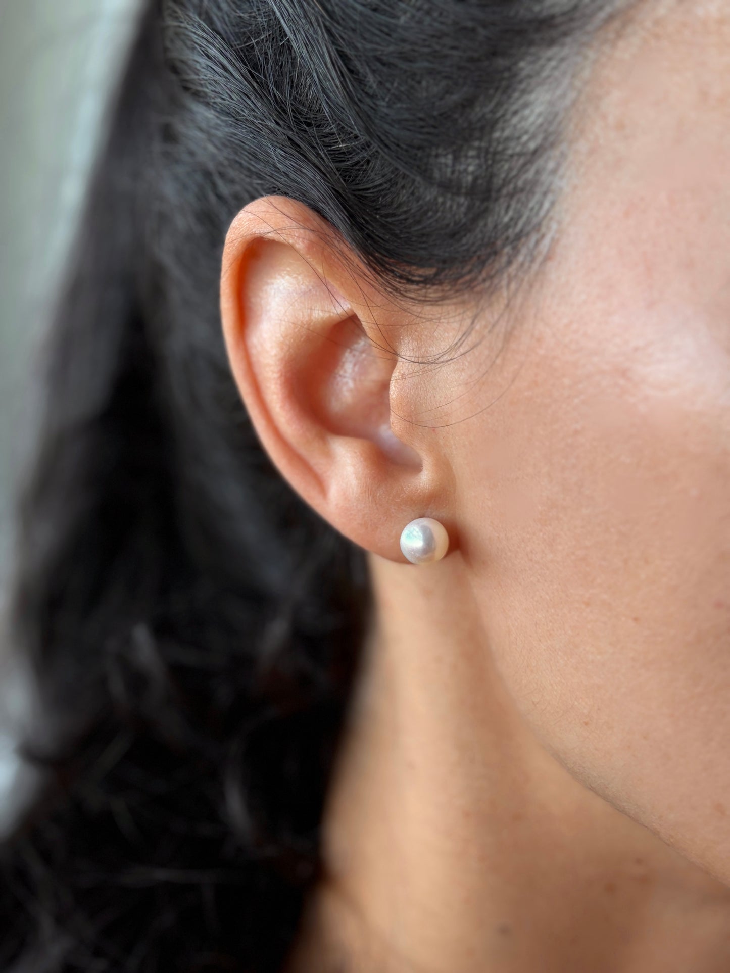 Close-up of women wearing Freshwater pearl stud earring with blurred background