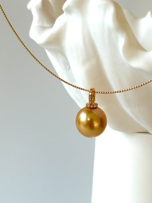Gold choker with a large round golden  south sea pearl pendant on a white marble bust.