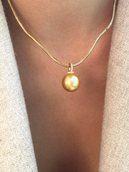 Gold necklace with a golden south sea pearl pendant on a blurred background