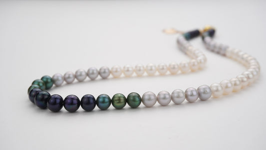 Strand necklaces with gradient pearls on a light gray background